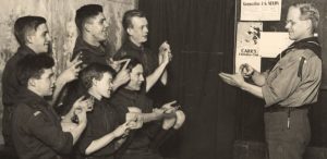 Type : Photograph Medium : Print-black-and-white Description : A view of boy scouts St. Mark's Deaf and Dumb Institute Westgate Road Newcastle upon Tyne taken c.1930. The photograph shows J. R. Richards Assistant Scout Master talking to a group of scouts using sign language.Youth Organisations Collection : Local Studies Printed Copy : If you would like a printed copy of this image please contact Newcastle Libraries www.newcastle.gov.uk/tlt quoting Accession Number : 022782
